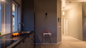 A modern kitchen with a black countertop, a sink, and a chair. - Bryggjur (Rangárþing eystra)