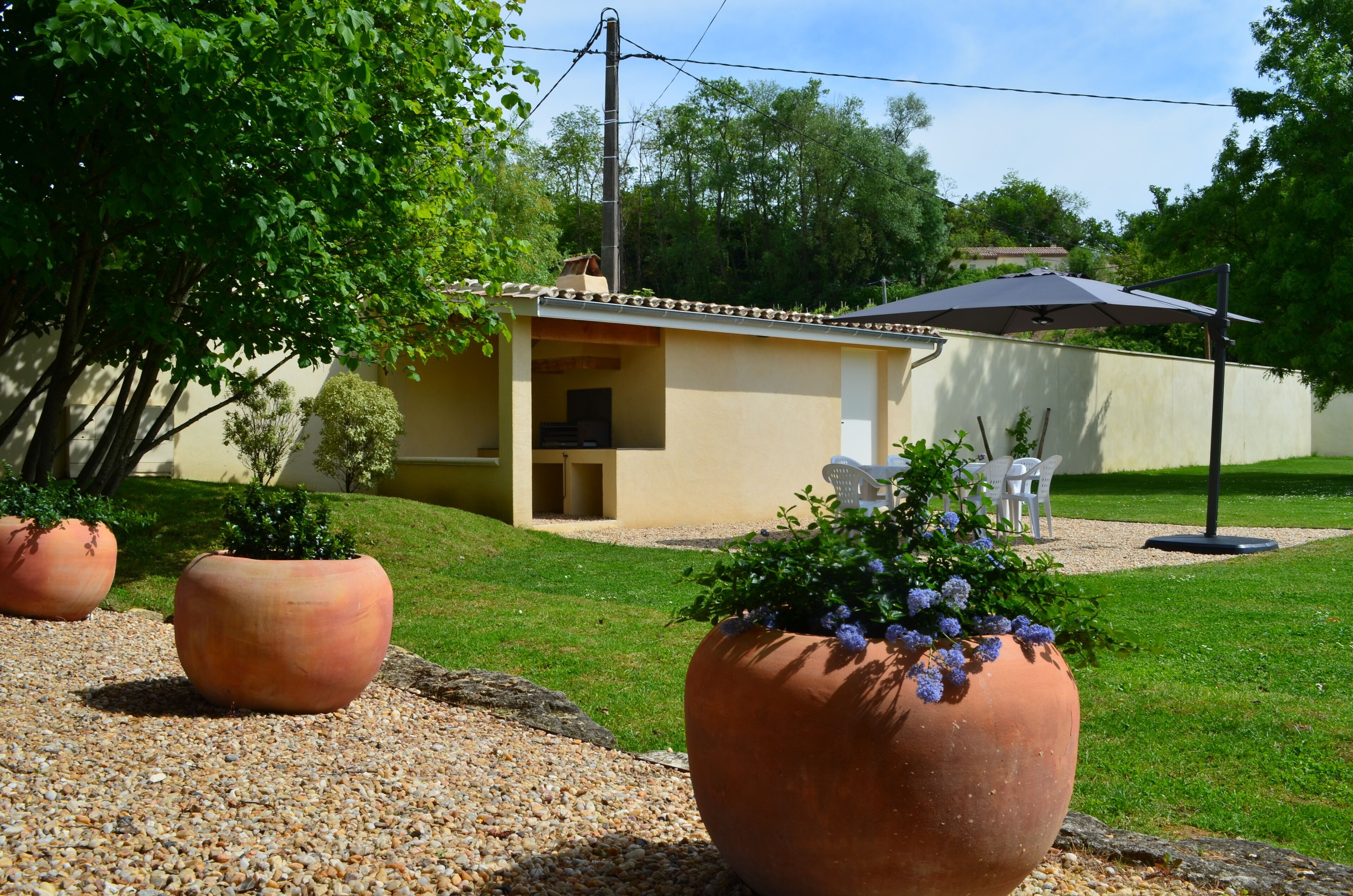 A house with a patio area, a small garden with potted plants, and a white chair.