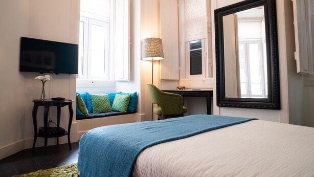 Habitación de hotel con cama, televisión montada en la pared, ventana con vistas, escritorio y silla.