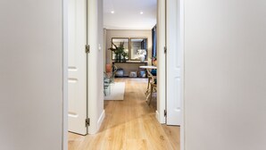A hallway with wooden flooring, white doors, and a dining area with a table and chairs.