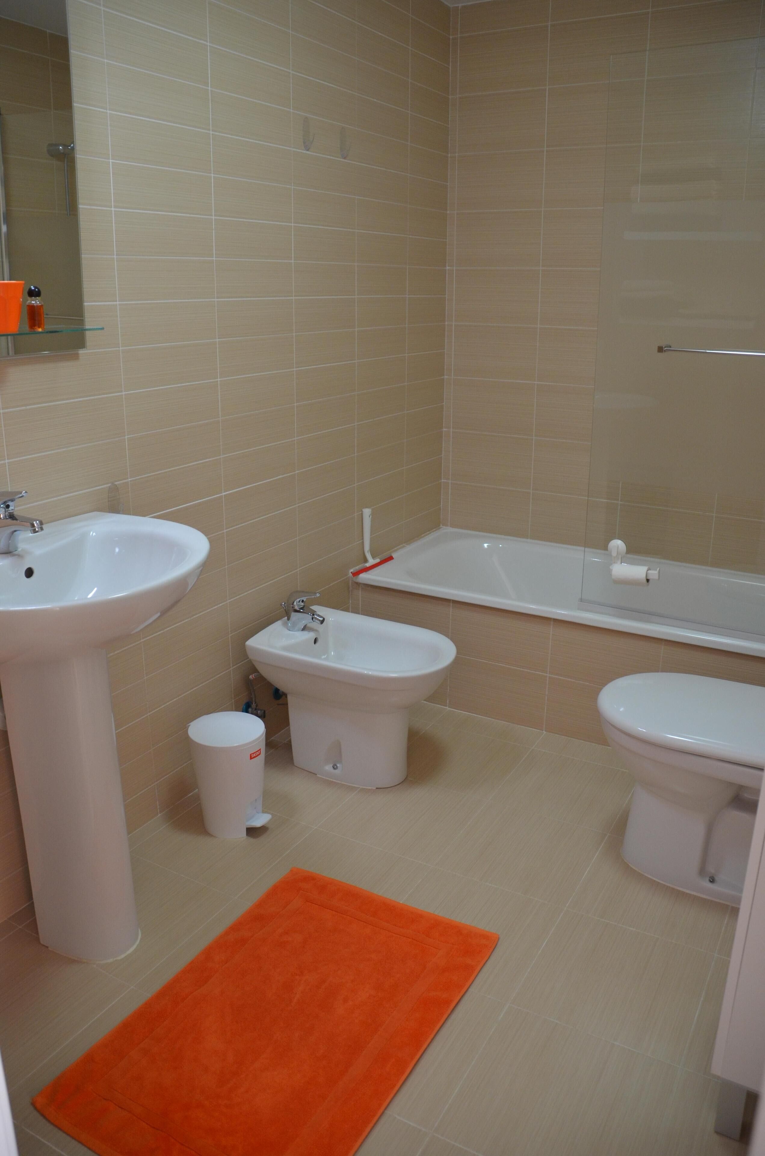 A bathroom with a sink, bidet, toilet, and bathtub.