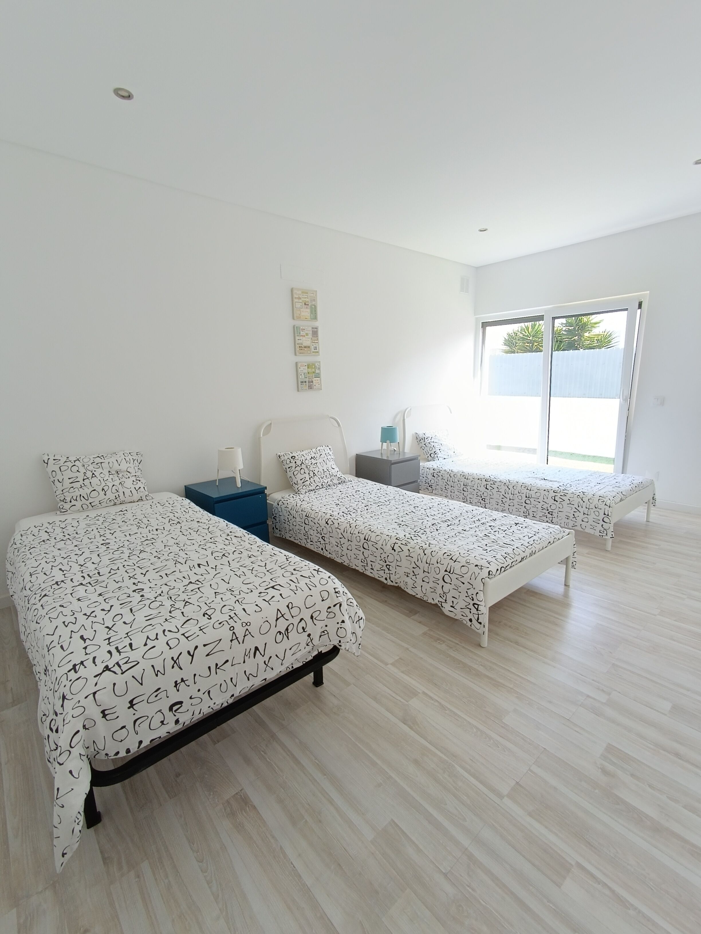 A bedroom with two beds, a desk, and a window.