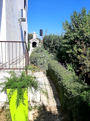 Un patio con sendero de piedra, valla metálica y setos verdes exuberantes.