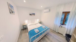 Una camera da letto con un letto, comodini, una finestra con tende e un condizionatore d'aria.