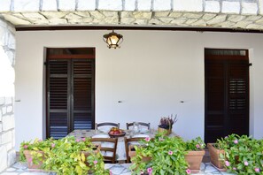 A covered outdoor dining area with a table set for two, surrounded by potted plants and a lantern above. - Holiday home Anna, Umag-Zambratija, near the beach, washing machine, parking (Zambratija)