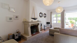 Ein Wohnzimmer mit Kamin, einer Couch, einem Fernseher und einem großen Fenster.