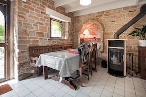 A stone-walled room with a fireplace, a bench, and a table with a tablecloth.