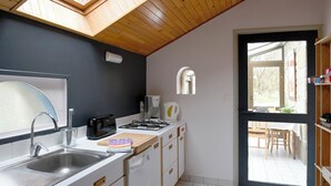 A compact kitchen with a skylight, a sink, a stove, and a window overlooking a garden.