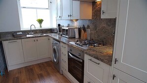 Una cocina con armarios blancos, horno empotrado, microondas y estufa a gas.