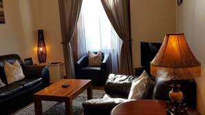 Una sala de estar con un sofá de cuero negro, una mesa de centro de madera, un sillón negro y una lámpara.