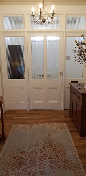 Traditional room with double doors, wooden floor, and a large rug.