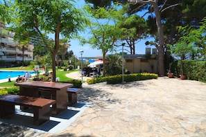 An outdoor patio area with stone flooring, benches, and potted plants.