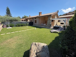 A house with a stone facade, a patio with outdoor furniture, and a well-maintained lawn.