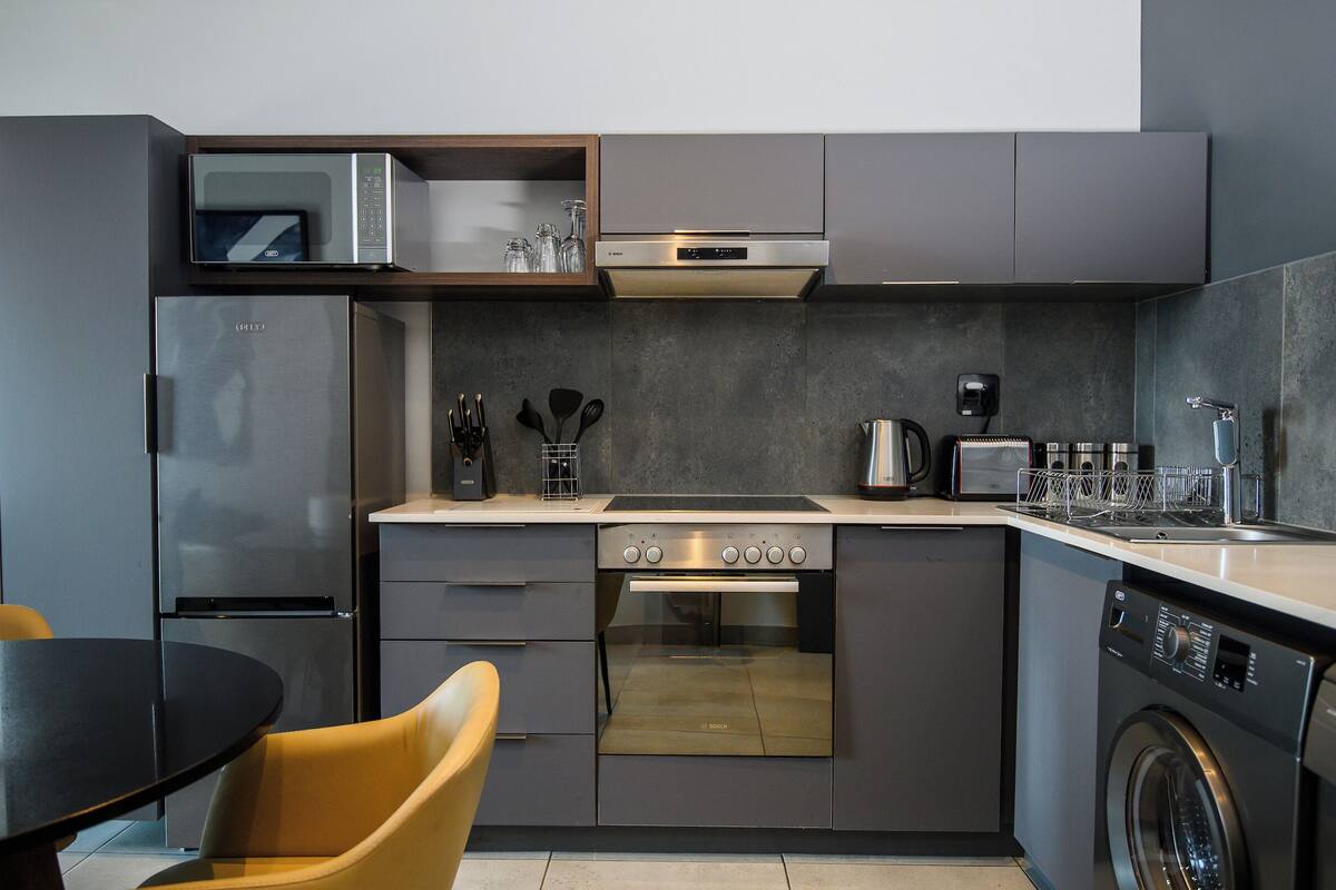Een kleine keuken met een inbouwoven, magnetron en vaatwasser.