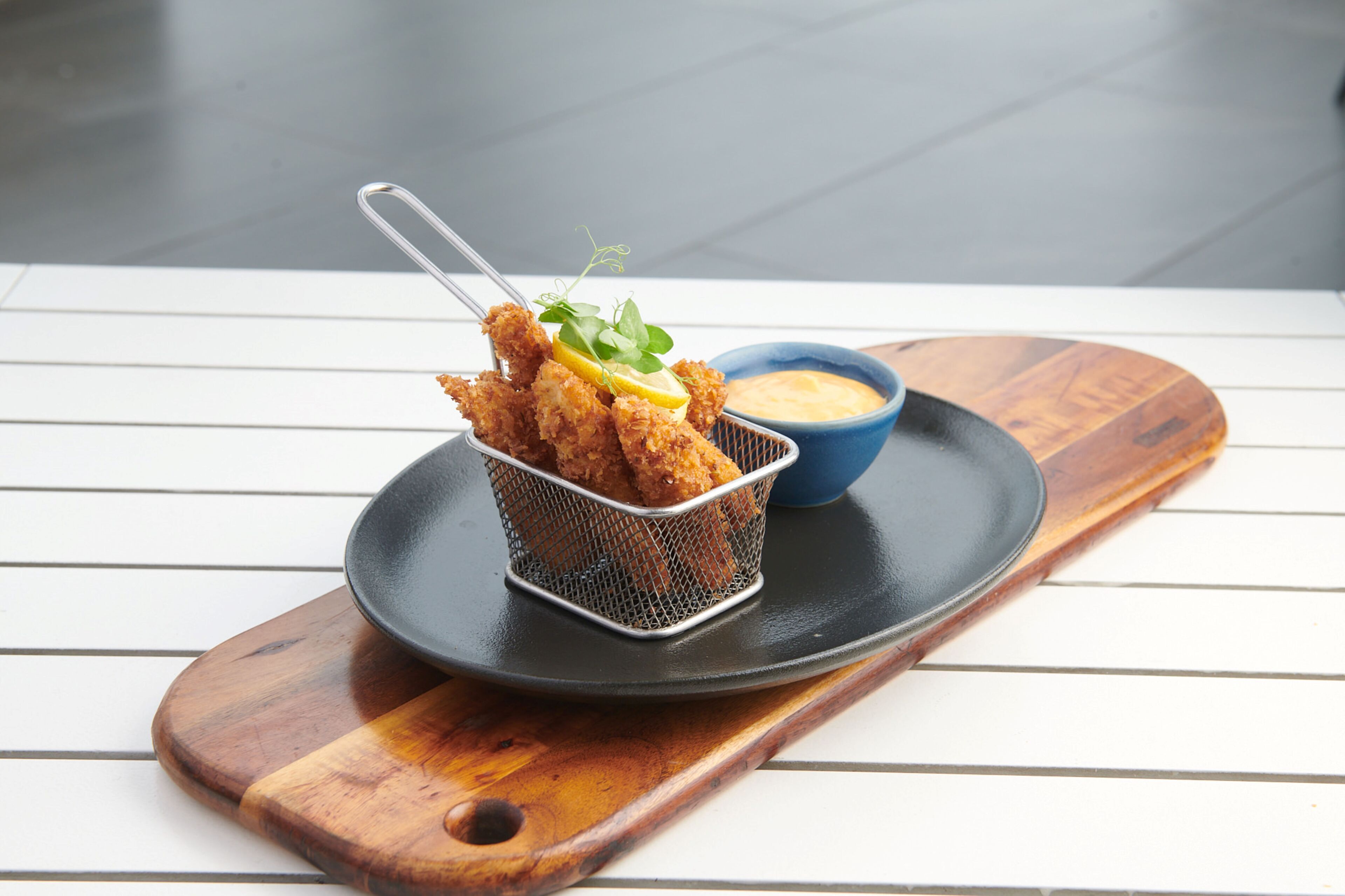 A tray with fried food and a dipping sauce on a wooden table.