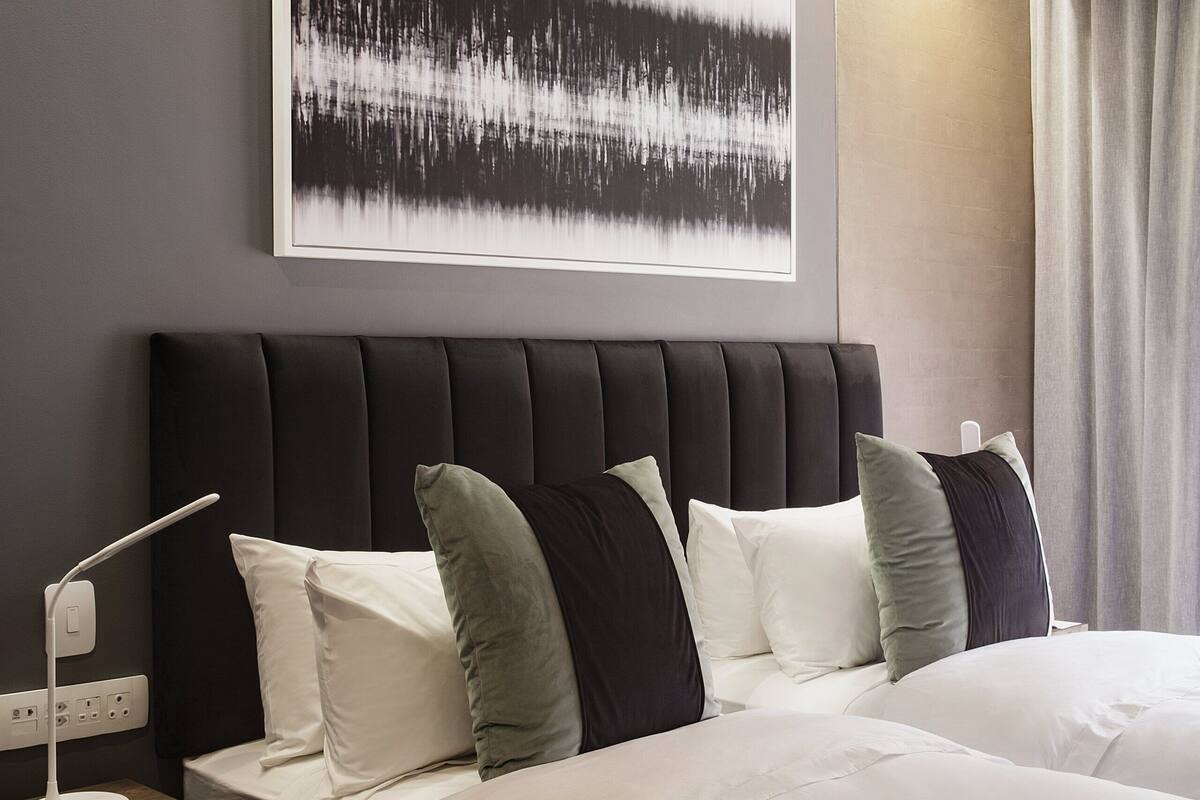 Een moderne hotelkamer met een groot bed, een nachtkastje met een lamp, een kunstwerk aan de muur en uitzicht op het landschap.