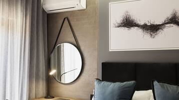 Una habitación de hotel moderna con una cama, un escritorio con una silla, un espejo redondo y un cuadro abstracto grande en la pared.
