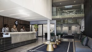 Een moderne hotel lobby met een receptiebalie, een zithoek en een trap naar een hoger niveau.
