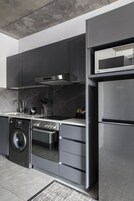 Una cocina moderna con electrodomésticos de acero inoxidable, armarios grises y una salpicadera de mármol.