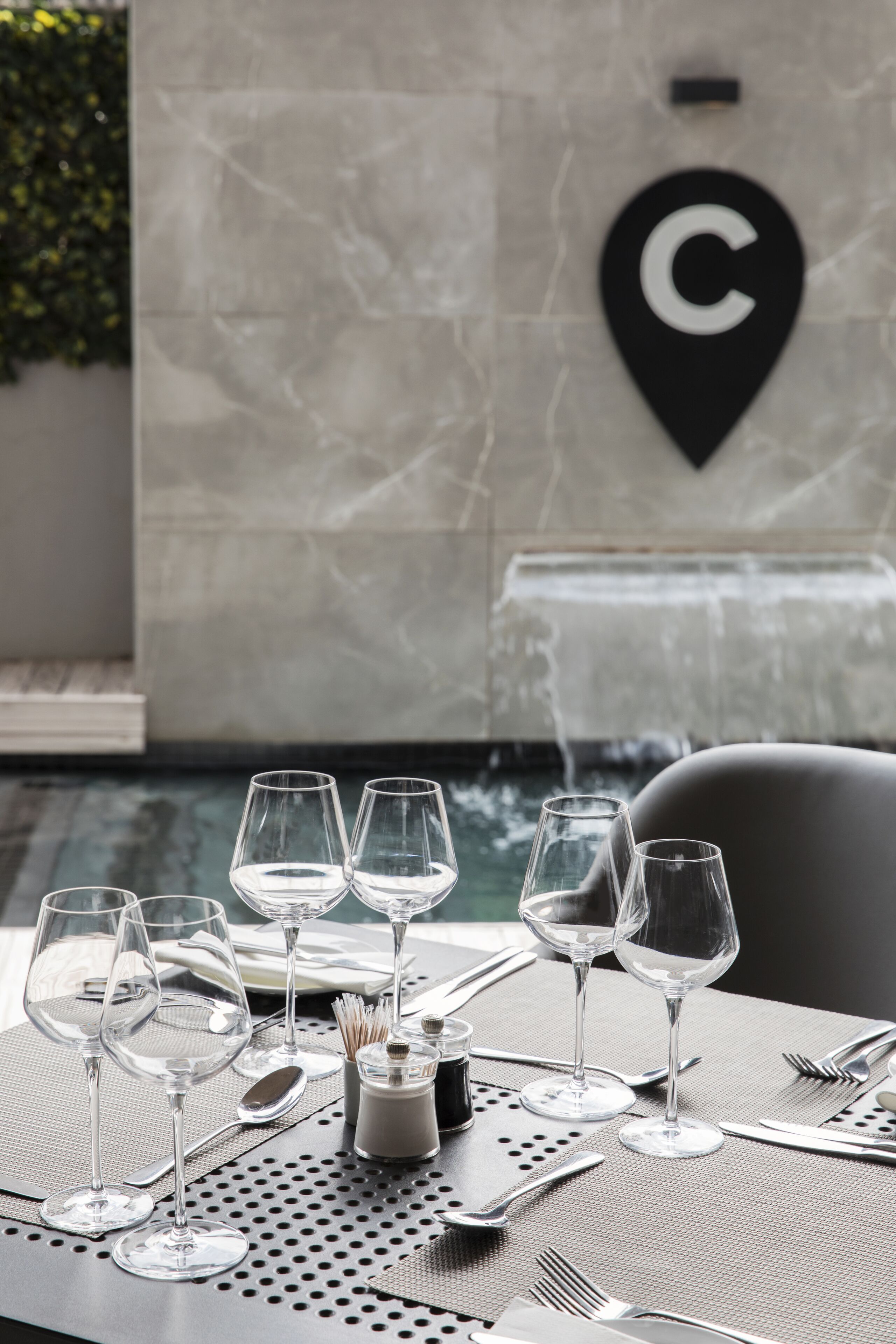 Una mesa de comedor dispuesta con copas de vino, cubiertos y salero y pimentero.