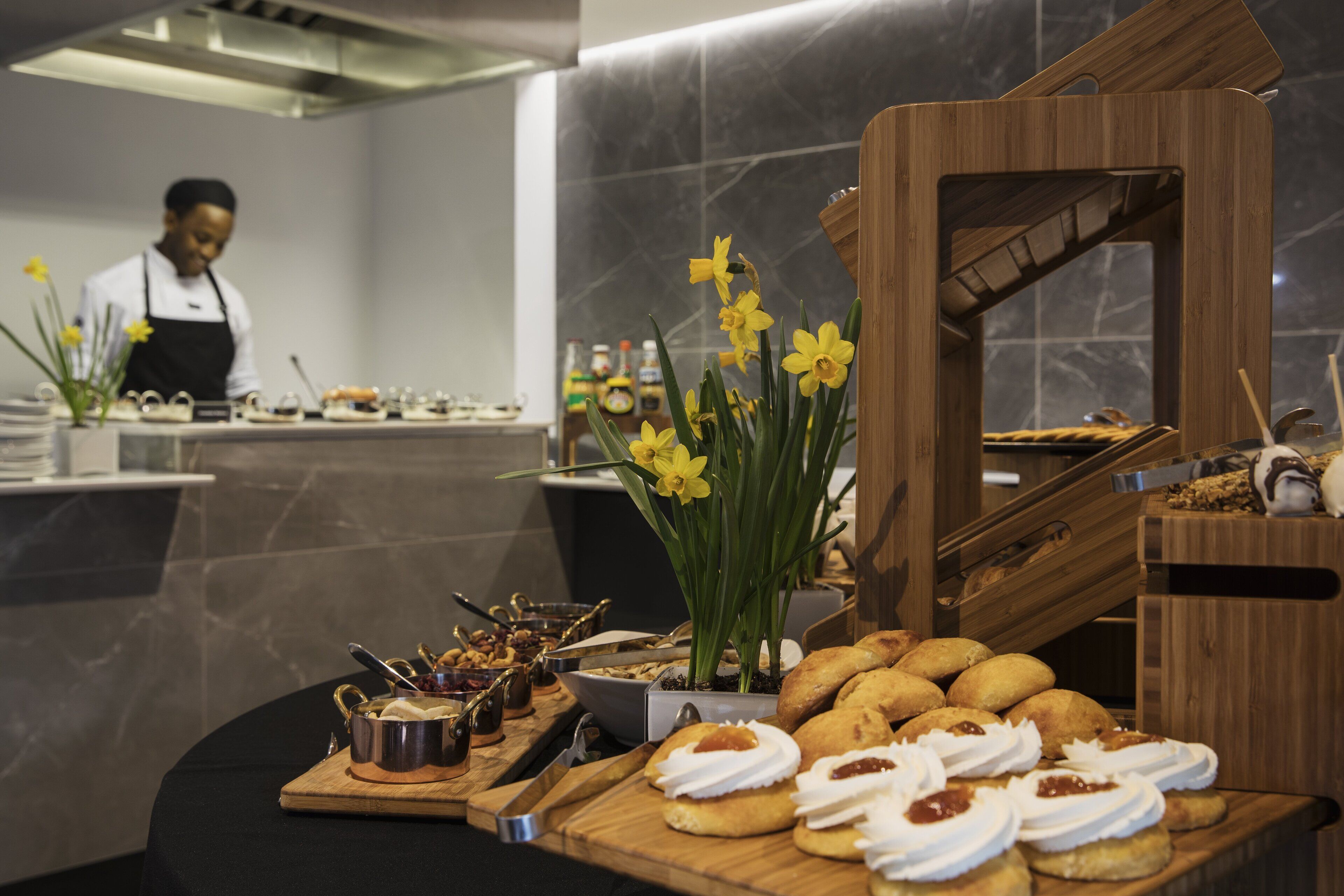 Un buffet proposant une variété de pâtisseries, avec un chef cuisinier en arrière-plan.