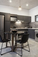 A modern kitchen with dark cabinetry, a round marble table, and black chairs.