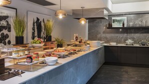 Een moderne keuken met een marmeren aanrechtblad, hangende lampen en diverse etenswaren en kruiden.