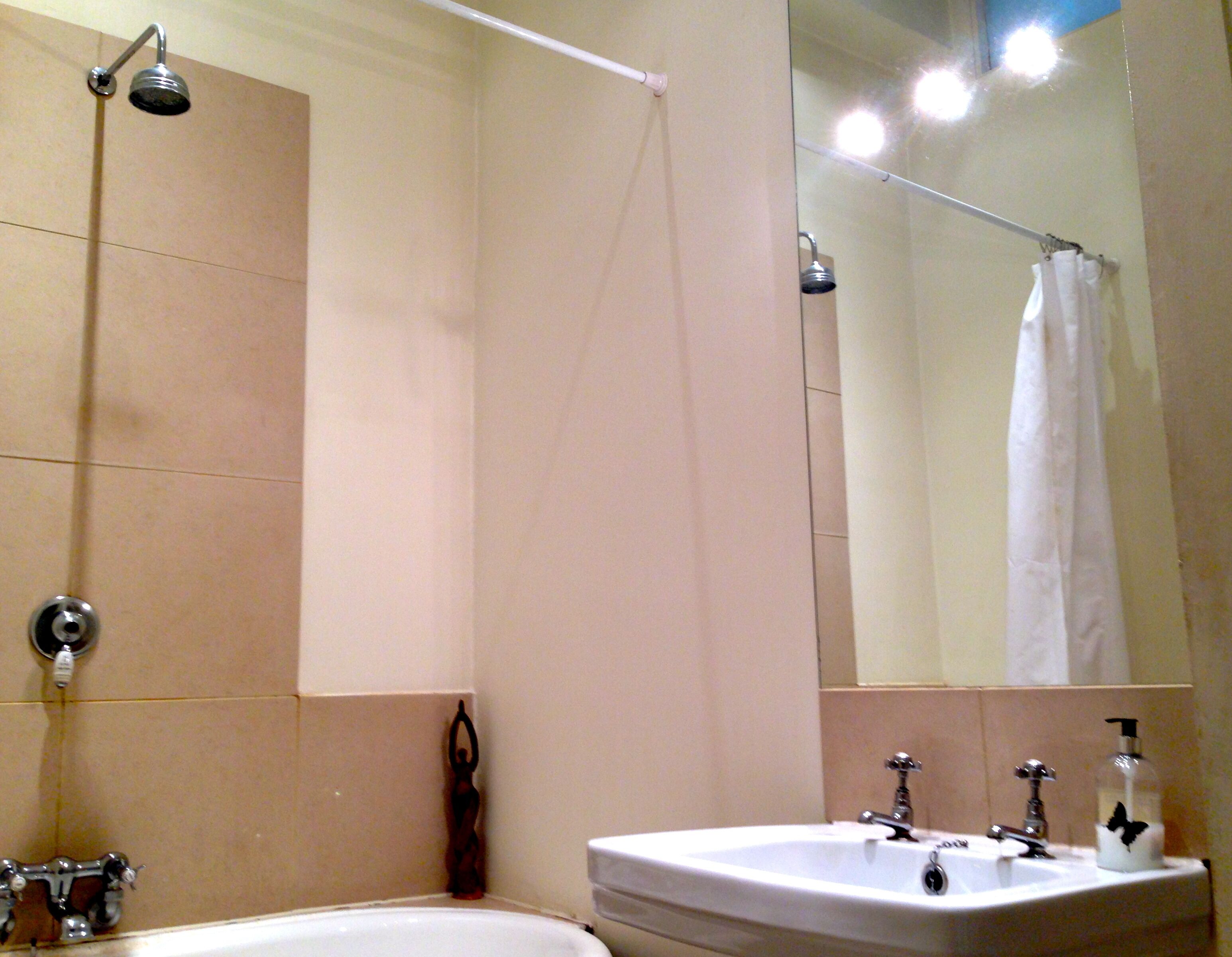 A bathroom with a bathtub, a shower, a sink, and a mirror.