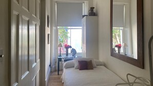Un dormitorio con cama, un espejo grande y una ventana.