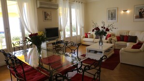 A living room with a glass dining table, a sofa set, and a TV. - Sea view, Beach-Front Cannes Apart, Central,  2 Bed/2 Bath,A/C,Parking, Wifi (Cannes)