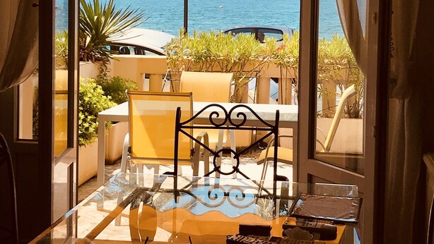 A room with a glass table, a chair, and a laptop. There is a view of the sea and a cruise ship in the background. - Sea view, Beach-Front Cannes Apart, Central,  2 Bed/2 Bath,A/C,Parking, Wifi (Cannes)