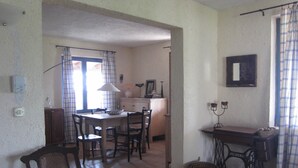 Een eethoek met een tafel, stoelen, een lamp, een klein kastje en een naaimachine.