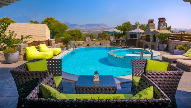 Un espace piscine aménagé avec des meubles en osier et offrant une vue sur les montagnes.