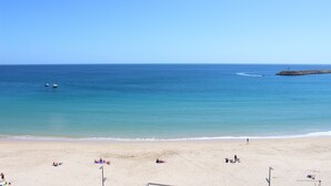 A beach with clear skies, calm waters, and a few boats. - Seazimbra - Luxury Apartment (Sesimbra)