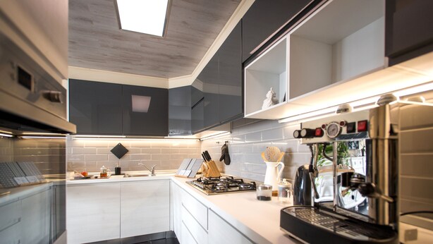 Una cocina moderna con cafetera espresso integrada, cocina a gas y salpicadero de azulejos.