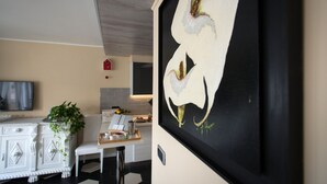 Una cocina moderna con un armario blanco, una mesa de comedor y un cuadro de flores blancas.