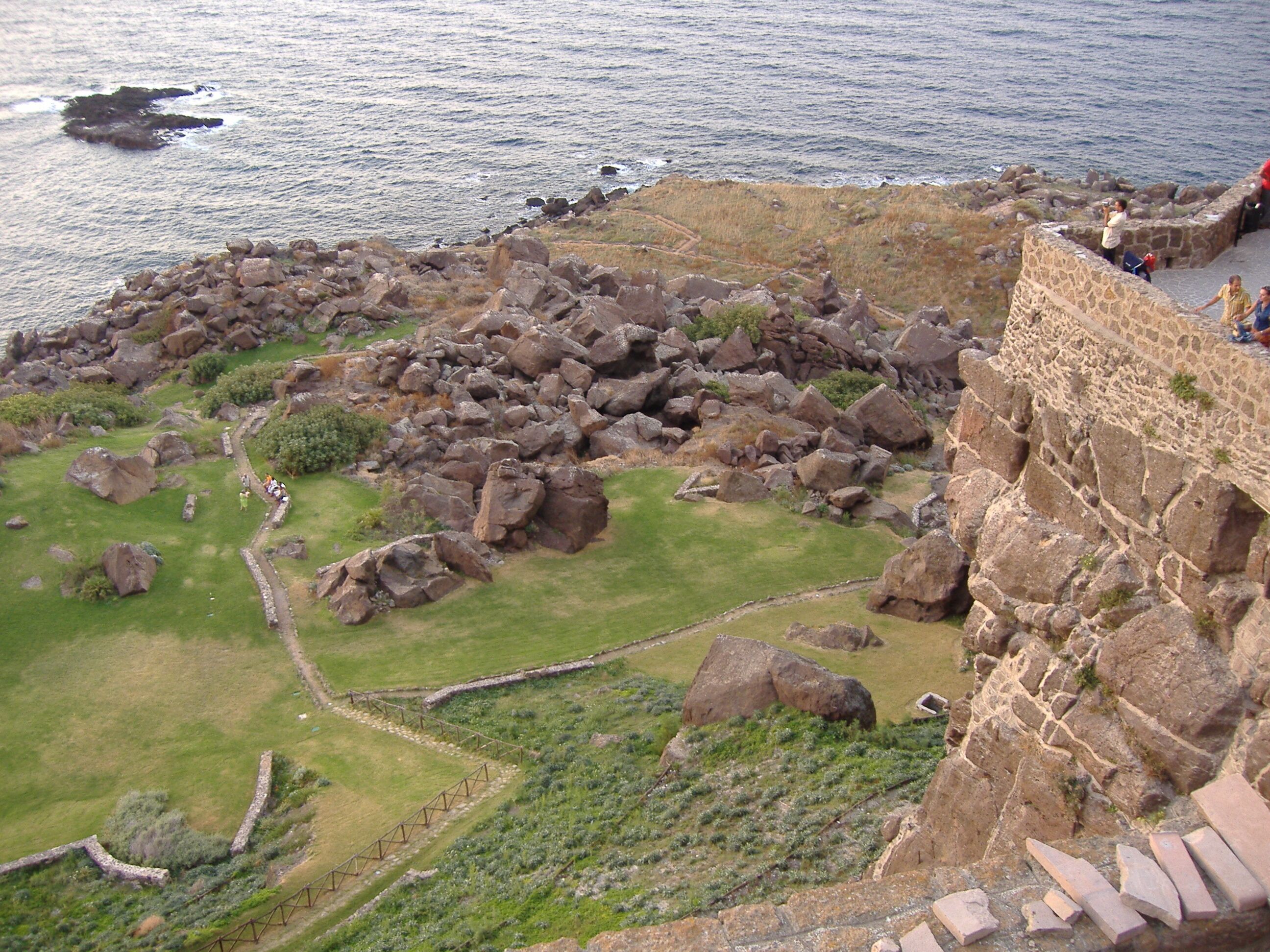 Un paysage côtier avec un mur de pierre et un terrain rocheux.