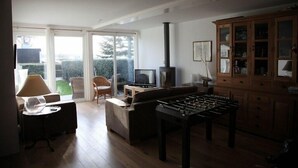 A living room with a sofa, a foosball table, a television, and a cabinet.