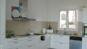 Een moderne keuken met witte kastjes, een inbouwoven, een raam met uitzicht en een spoelbak.