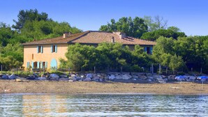 Ein Haus mit Ziegeldach, gelegen am Ufer eines Sees mit steiniger Uferlinie.