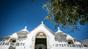 A white building with a central arched doorway and two small windows on either side.