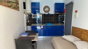 A compact room with a kitchenette, a bed, and a dining area.