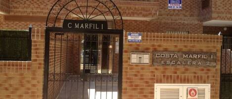 A gated entrance with a sign reading "COSTA MARFIL I ESCALERA 2".