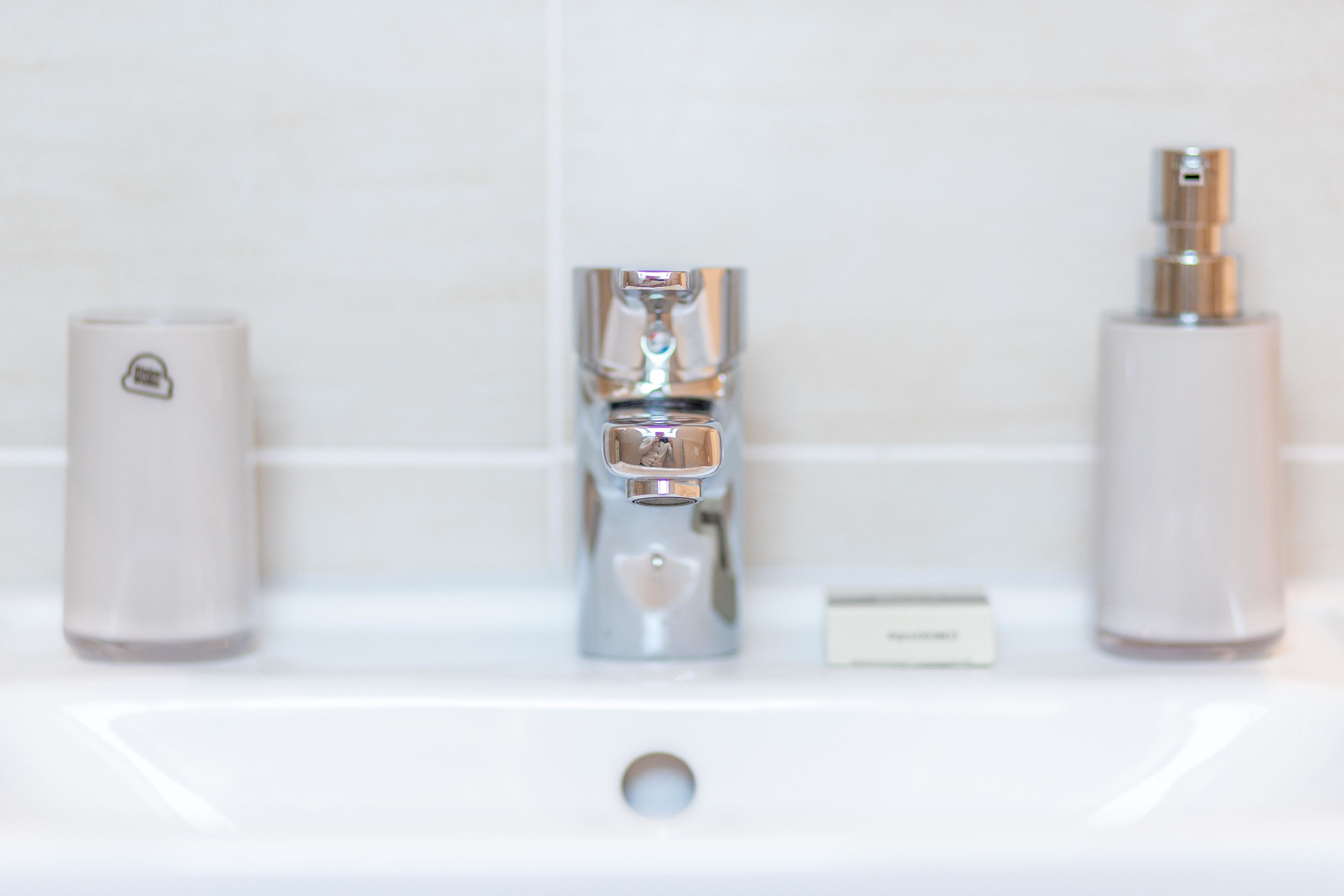 A bathroom sink with a modern faucet, a soap dispenser, and a bottle of liquid soap.