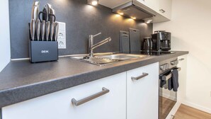 A modern kitchen with a stainless steel sink, a coffee machine, and a knife block. - Ferienwohnung Anton Greetsiel (Krummhoern)