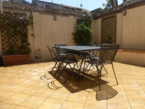 A patio with a table and chairs, surrounded by walls and a tiled floor.
