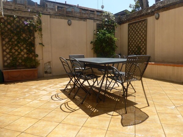 A patio with a table and chairs, surrounded by walls and a tiled floor. - Stylish Duplex with Stunning Private Courtyard in Dorsoduro (Venice)