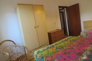 Une chambre à coucher comprenant un lit, une armoire, une chaise et une commode.