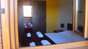 Une chambre d’hôtel avec un lit, un miroir, une armoire en bois et une table avec des serviettes.