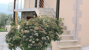 Un bâtiment à deux étages doté d’un balcon, d’un escalier et d’un petit jardin.